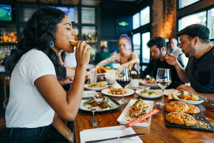 Kvinne som er ute å spiser pizza og drikker vin med vennene sine på en restaurant